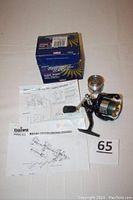 Daiwa Regal 2000 Xi spinning reel with extra spool, original box and instruction sheets laid out on a flat white surface. Shows condition and completeness of the lot.