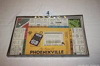 Top view of the sealed Game of Phoenixville board game showing the colorful game board under plastic wrap with visible text and logos.