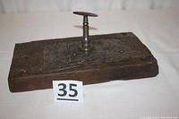 Top view of the antique door lock mounted on a wooden plank showing the keyhole and key inserted vertically.