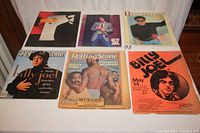 Photo showing six items: three tour programs, two Rolling Stone publications, and one concert poster