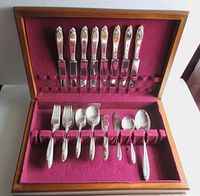 Wooden box with burgundy velvet interior showing entire 52-piece flatware set.