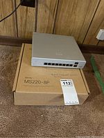 Meraki MS220-8P switch on original box showing front ports and overall condition.