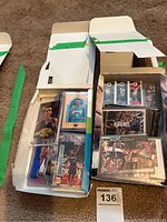 Opened boxes filled with basketball cards organized in sleeves and protective holders, showing various players and brands including Penny Hardaway focus.