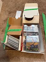 Two cardboard boxes containing sleeved trading cards and loose cards in protective sleeves.