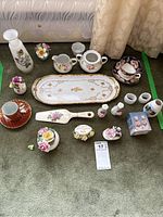 Full view of the china collection showing floral arrangements, cake plate, server, cream, sugar, teacup, saucer, napkin rings, and other items.