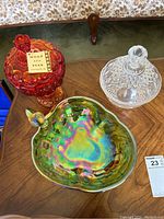 Photo of the three glass collectible items on a wooden table showing the red Moon and Star jar, the crystal bowl, and the iridescent apple dish.