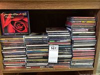 Full view of CD collection stacked on a wooden shelf with visible titles.