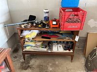 Overview of cabinet contents showing red milk crate on top, straps, tools, and various small items.