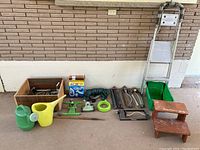 Full display of gardening lot showing step ladder, watering cans, hose parts, sprinklers, garden box and foot stools