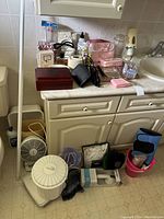 Overview of bathroom items on vanity and floor including wooden box, electric shaver, heaters, buckets, knee supports.