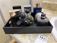Lot of men's fragrance bottles displayed in a black tray on a marble countertop