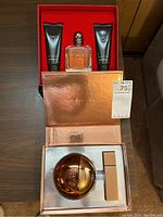 Both fragrance gift sets in their respective boxes on wood table