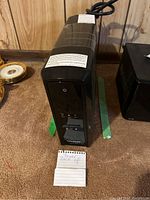 Front and top angled view of CyberPower UPS black unit on carpeted floor with handwritten note labeled 'Power Back Up'