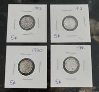 Four Canadian 5 cent coins dated 1903, 1913, 1920, and 1941 mounted in individual white cardboard holders viewed from the reverse sides showing the coin date and denomination.