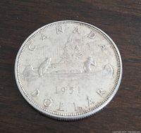 Obverse side of the 1951 Canadian silver dollar coin showing the canoe with two paddlers and the inscription 'CANADA DOLLAR 1951'.
