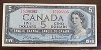 Front side of the 1954 Canadian five dollar banknote showing Queen Elizabeth II portrait, red serial numbers, and denomination details.