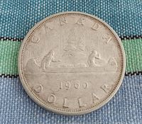 Front of 1960 Canadian silver dollar coin showing voyageurs in a canoe with date 1960 and 'CANADA DOLLAR' inscription.