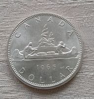 Reverse side of the 1965 Canadian silver dollar displaying the voyageur canoe scene with the year 1965 and inscriptions.