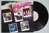 Vinyl record album 'Number 1 Hits of the Eighties' with front cover showing artist pictures and colorful design, plus the vinyl record disc surface and label.