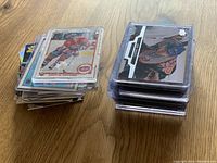 Two stacks of hockey trading cards on a wooden surface, some cards in plastic holders showing varied formats and eras