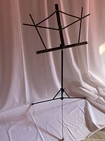 Front view of the black adjustable music stand showing its height and foldable sheet holder design
