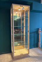 Front view of the tall glass display cabinet showing glass doors and shelves inside.