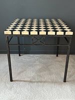 Front view of the square side table showing checkerboard stone top and full wrought iron base.