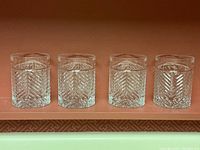 Front view of four cut crystal glasses in a row showing overall set and pattern