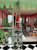 Full height view of obelisk shelving unit next to sliding glass door, showing overall shape and finish