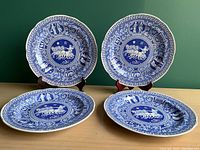 Four 10-inch ceramic plates with a detailed blue and white Greek pattern featuring chariots, vases with classical figures, and a Greek key border.