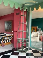 Full-height view of green obelisk plant stand in room setting