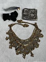 Full view of all four items including a gold sequin collar, leopard scarf, black rhinestone barrette and black feather fascinator