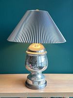 Full view of the vintage blown glass lamp with chrome finish on base and metallic pleated chrome lampshade.