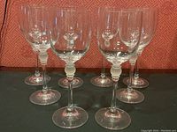 Set of eight crystal wine glasses arranged in two rows showing clear bowls and frosted stem detail.