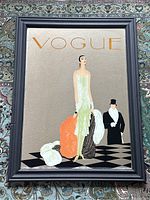 Full front image of the 1980s Art Deco revival style Vogue mirror showing the woman in a pale green flapper dress holding orange and white fur stoles with a man in formal black attire and top hat behind her.