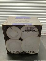 Factory-sealed box of China Pearl 20-piece fine china dinner set with images of plates shown on the box.