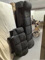 Photo of two black fabric couch seating sections with tufted cushions, placed upright in a storage area surrounded by boxes and other household items.