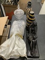 Photo of assorted decorative vases and black glass figurines on a tabletop, showing shapes, colors, and materials.