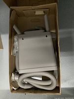 Top-down photo of the Kirby vacuum unit in a box, showing coiled flexible hose and accessories packed inside.