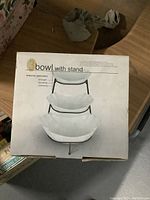 Box top showing label and image of three porcelain bowls stacked on a black metal stand