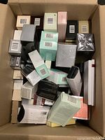 Overhead image of a cardboard box filled with various boxed skincare, fragrance items, and jewelry boxes of different sizes and colors.