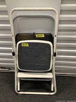 Two small white metal step stools with black rubber tops stacked together in folded position.