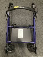 Full view of blue Drive walker with seat and wheels on gray carpet