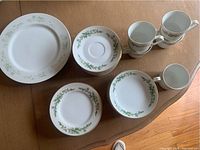 Top view showing a large plate, several smaller plates, and three stacked tea cups with floral and gold trim design.