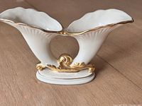 Side view of white dual flower vase with fluted open tops and gold trim showing details of the connecting base.