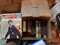 Top view of the box showing 14 assorted books including several popular science titles, cookbooks, and classic novels.