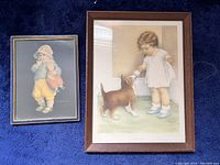 Two framed prints of children on a blue carpet background - larger print by Bessie Pease Gutmann shows a child giving treat to dog; smaller print by Frances Tipton Hunter shows child holding doll.