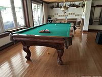 Full view of pool table with racked balls and cue ball at foot end