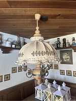 Ceiling light fixture with fabric shade, embroidered pattern, and wood and metal details seen from below and side angles.