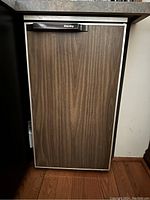 Closed view of Danby bar fridge showing wood grain door and black handle